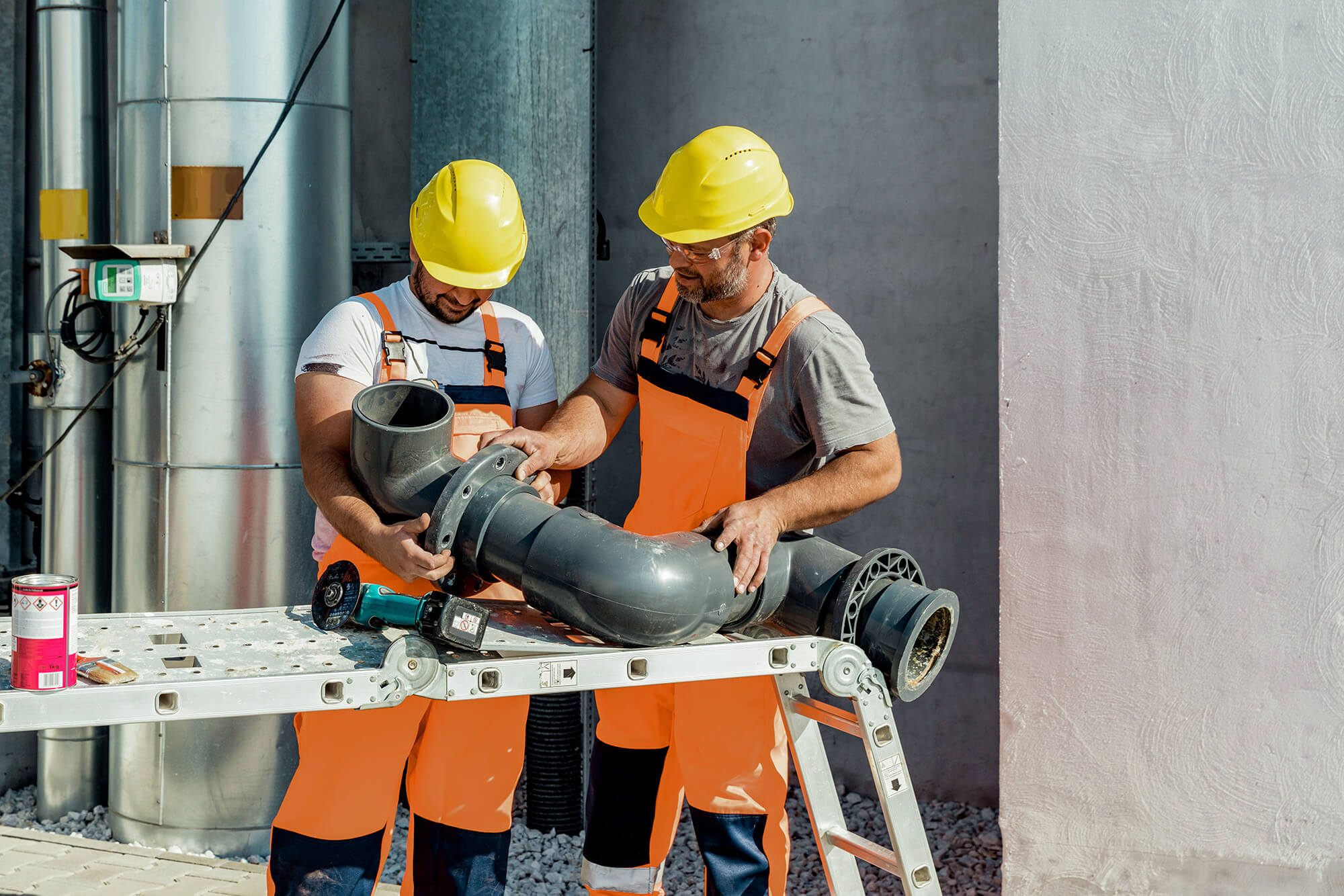 Two trade workers assembling a pipe.