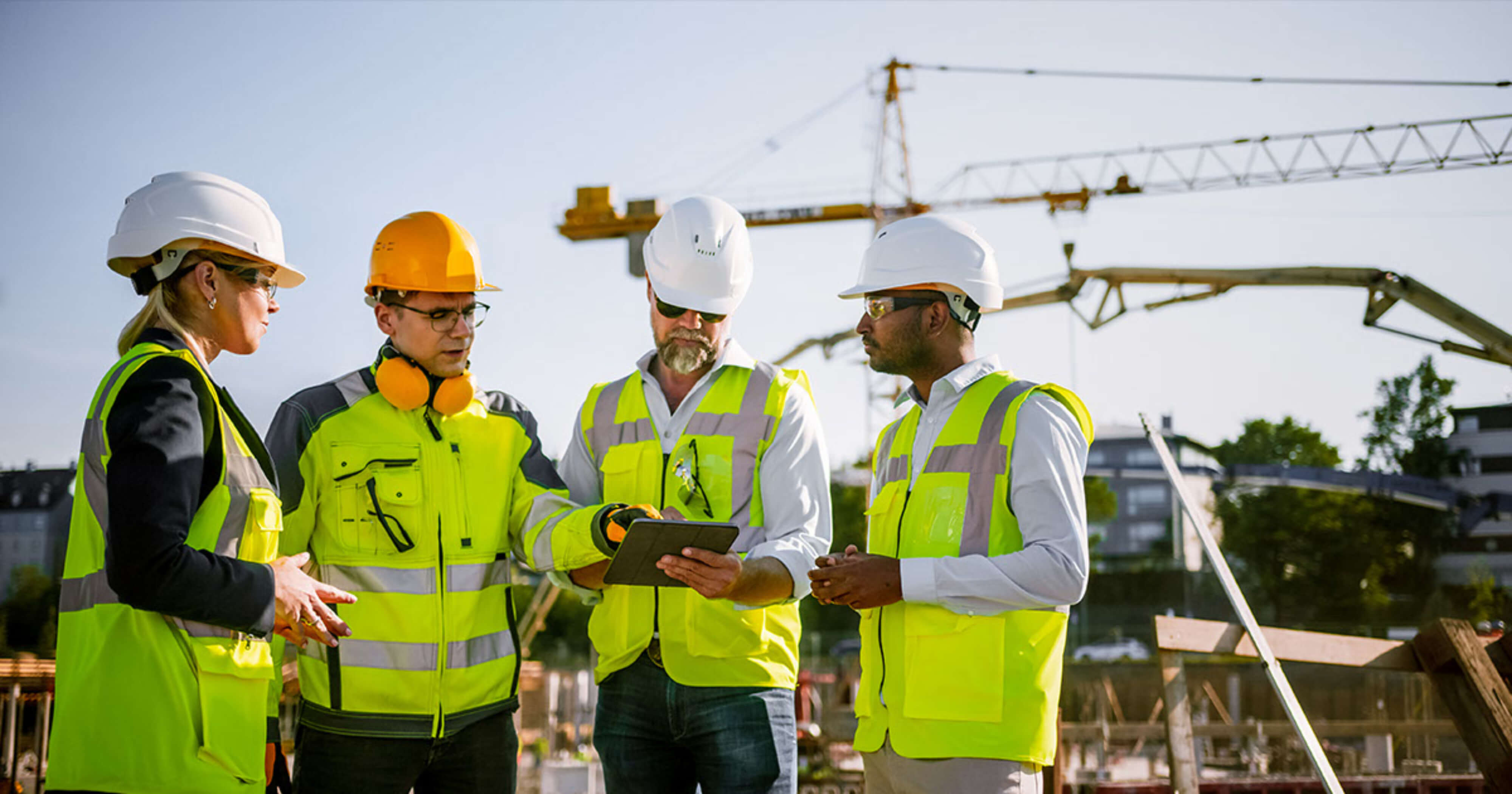 four contracters looking at project plans on a tablet.