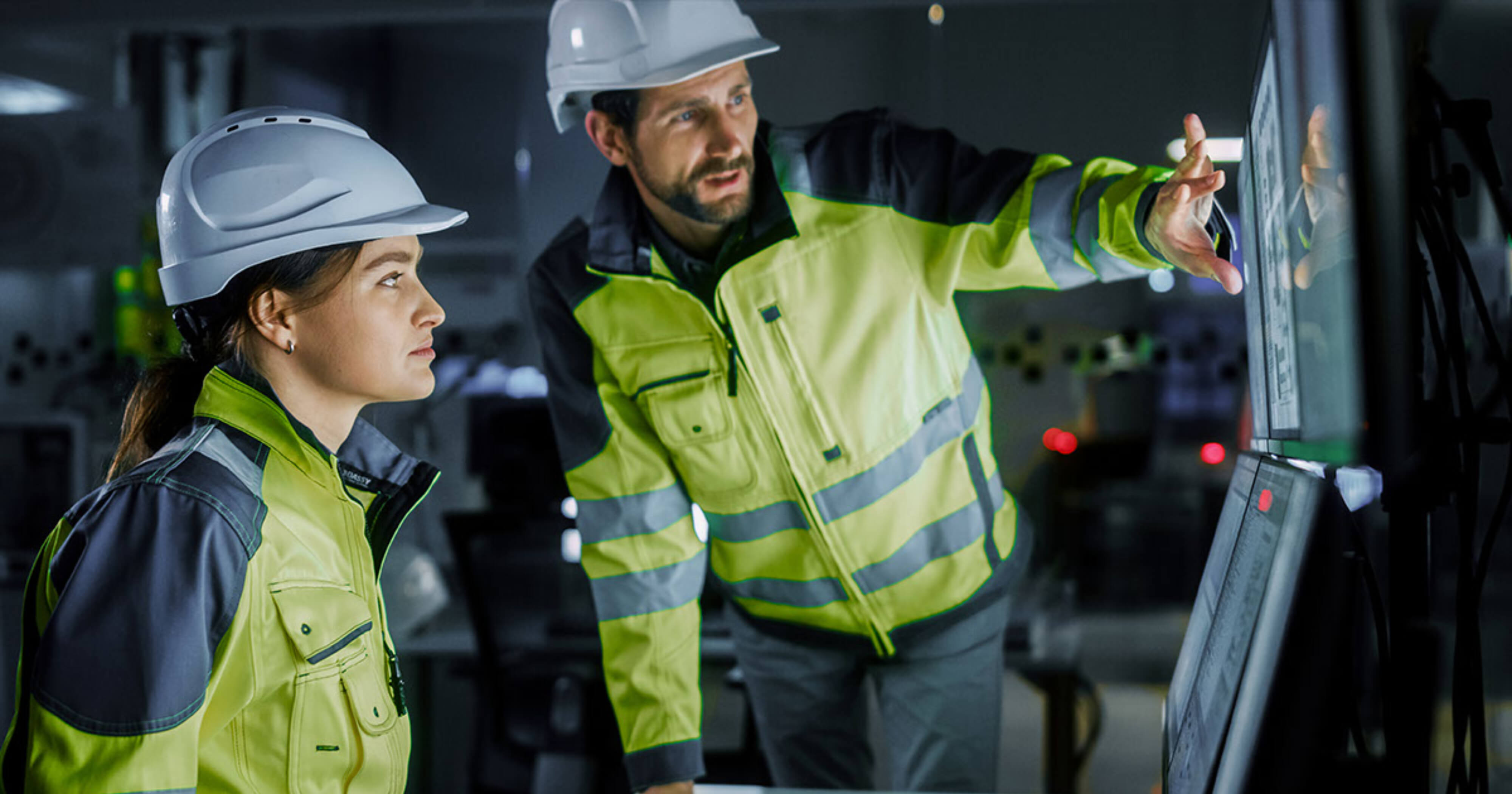 Two trade workers looking at computer screens.