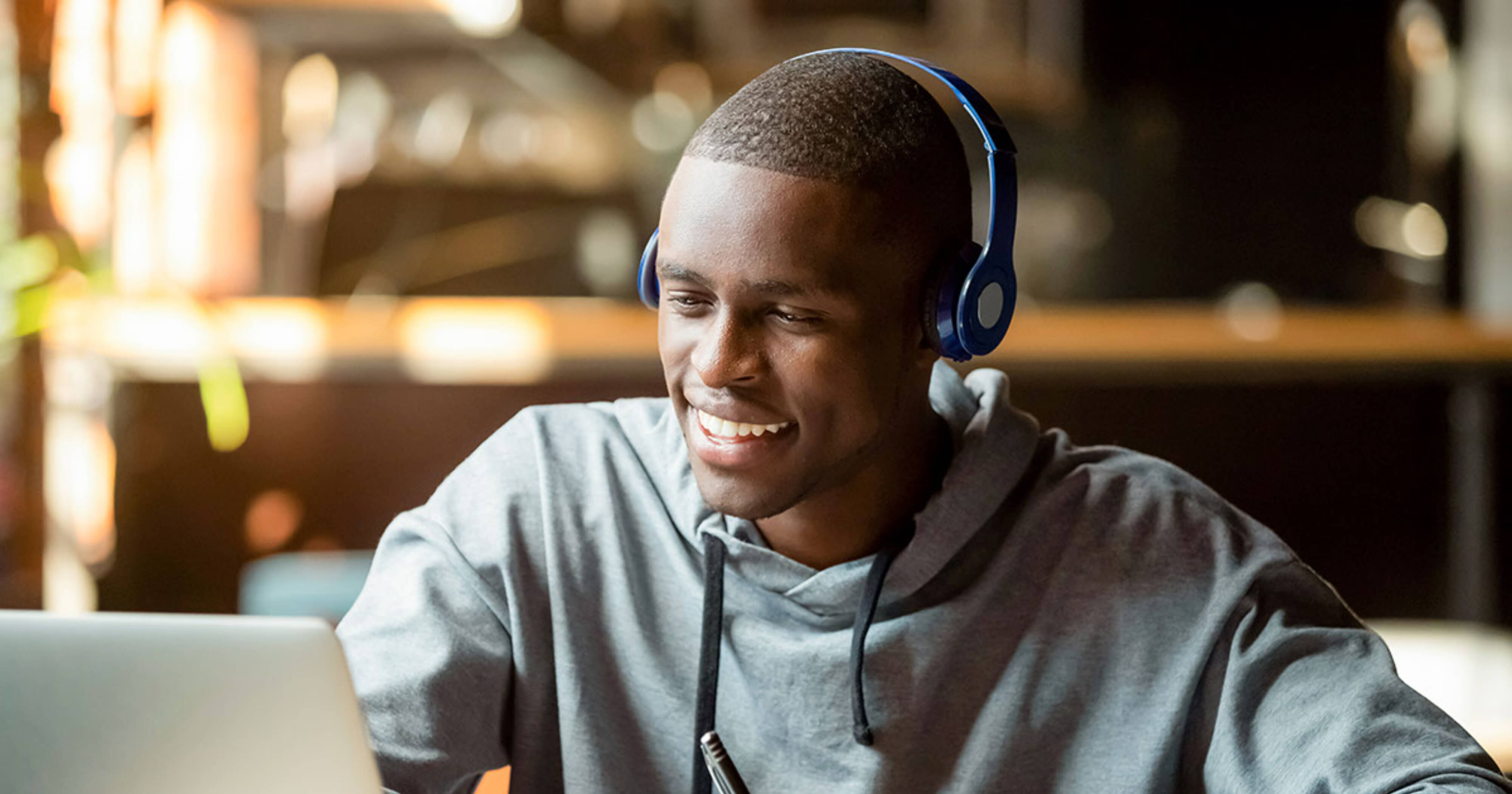 Man wearing headphones looking at laptop.