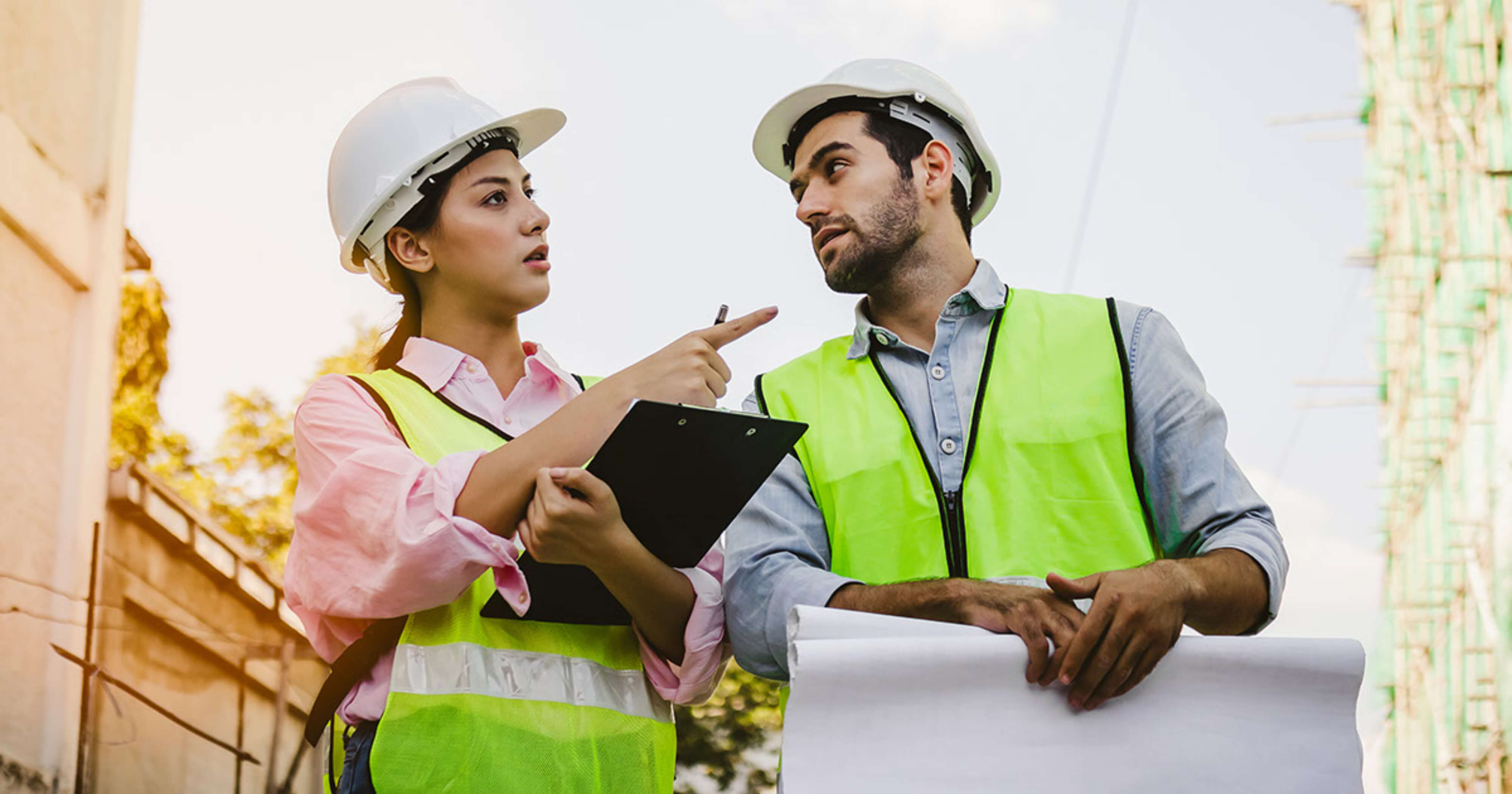 Woman and man construction workers discussing blueprints.